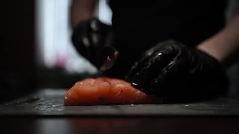 Close-Up of Hands Slicing Fresh Salmon Fillet on a Dark Background Stock-Footage 303925468