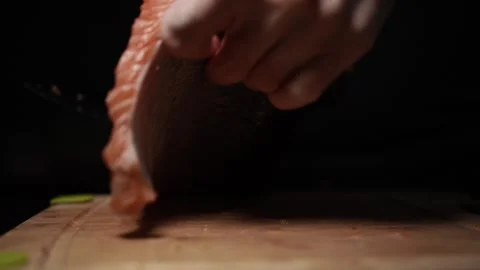 Close-Up of Hands Slicing Fresh Salmon Fillet on a Dark Background Stock Footage 303926092