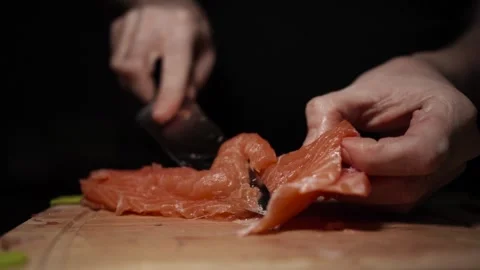 Close-Up of Hands Slicing Fresh Salmon Fillet on a Dark Background Stock Footage 303926096