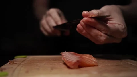 Close-Up of Hands Slicing Fresh Salmon Fillet on a Dark Background Vídeos de archivo 303926098