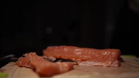 Close-Up of Hands Slicing Fresh Salmon Fillet on a Dark Background Stock Footage 303926112