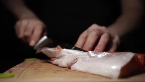 Close-Up of Hands Slicing Fresh Salmon Fillet on a Dark Background Video stock 303926115