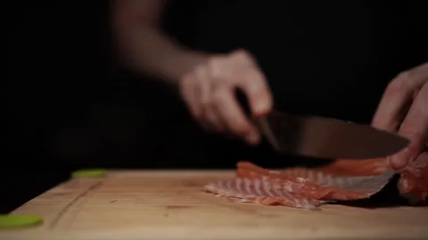 Close-Up of Hands Slicing Fresh Salmon Fillet on a Dark Background Stock Footage 303926129