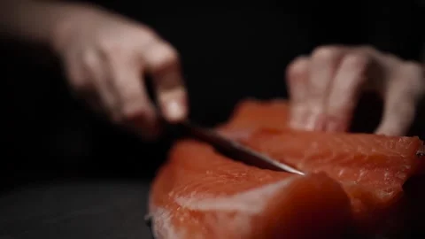 Close-Up of Hands Slicing Fresh Salmon Fillet on a Dark Background Stock Footage 303926145