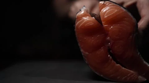Close-Up of Hands Slicing Fresh Salmon Fillet on a Dark Background Video stock 303926154