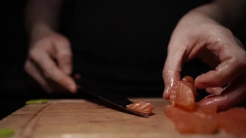 Close-Up of Hands Slicing Fresh Salmon Fillet on a Dark Background Video stock 303926224