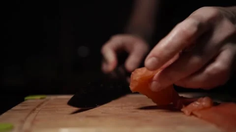 Close-Up of Hands Slicing Fresh Salmon Fillet on a Dark Background Video stock 303926225