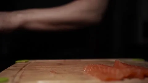 Close-Up of Hands Slicing Fresh Salmon Fillet on a Dark Background Stock Footage 303926239