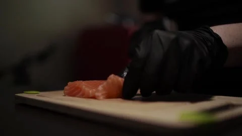Close-Up of Hands Slicing Fresh Salmon Fillet on a Dark Background 스톡 동영상 303926360
