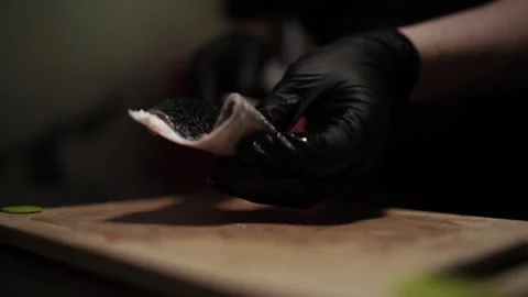 Close-Up of Hands Slicing Fresh Salmon Fillet on a Dark Background Видео 303926384
