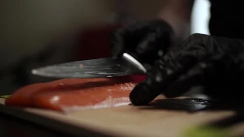 Close-Up of Hands Slicing Fresh Salmon Fillet on a Dark Background Video stock 303926385