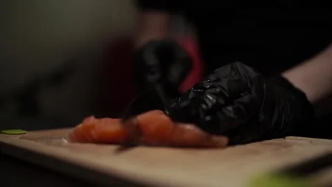 Close-Up of Hands Slicing Fresh Salmon Fillet on a Dark Background Stock Footage 303926408