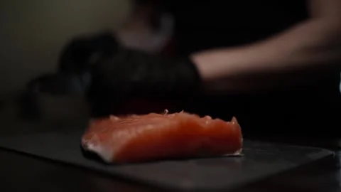 Close-Up of Hands Slicing Fresh Salmon Fillet on a Dark Background Stock Footage 303926438