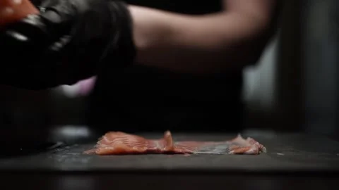 Close-Up of Hands Slicing Fresh Salmon Fillet on a Dark Background Stock Footage 303926464