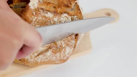 Close Up of Hands Slicing Fresh Sourdough Bread on Wooden Board Stock Footage 337281265
