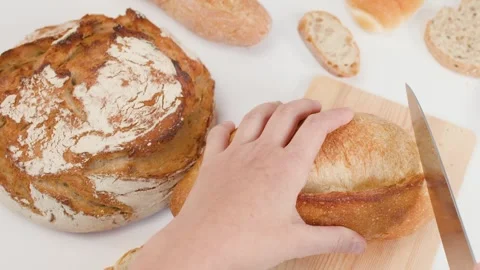 Close Up of Hands Slicing Fresh Sourdough Bread on Wooden Board Stock Footage 337519122