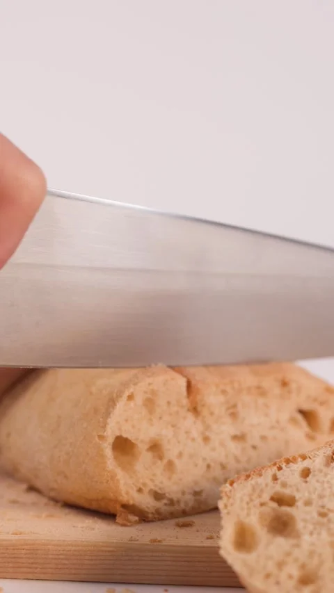 Close Up of Hands Slicing Fresh Sourdough Bread on Wooden Board Stock Footage 337690959