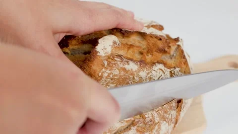 Close Up of Hands Slicing Fresh Sourdough Bread on Wooden Board Stock Footage 337875288