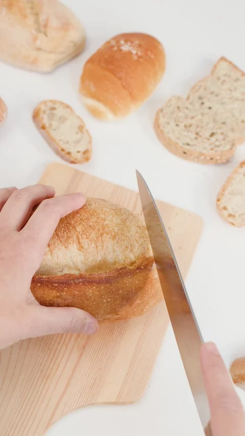 Close Up of Hands Slicing Fresh Sourdough Bread on Wooden Board Stock Footage 338326791
