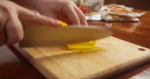 Close up of hands slicing fresh yellow bell pepper into thin strips with a Stock Footage 335823199