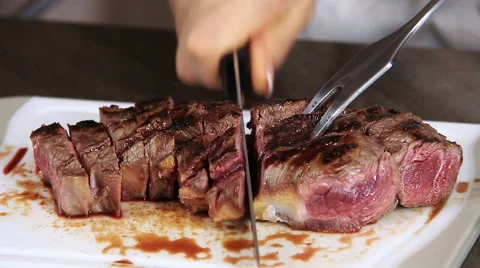 Close up on hands Slicing of a grilled steak on a cutting board: slicing an beef Stock Footage 61356810