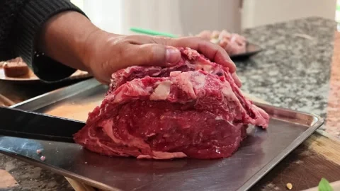 Close Up of Hands Slicing Raw Beef with a Knife for Traditional Argentine Asado Stock Footage 344352404
