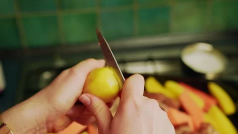 Close-up of hands slicing a raw potato with a paring knife in a home kitchen Video stock 328873973