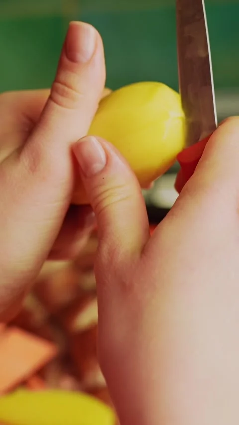 Close-up hands slicing a small yellow potato with a knife, making two quick Stock Footage 331467599
