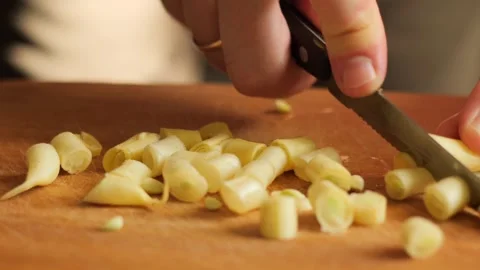 Close-up of hands slicing yellow beans with a knife on a wooden board for health Stock Footage 313564909
