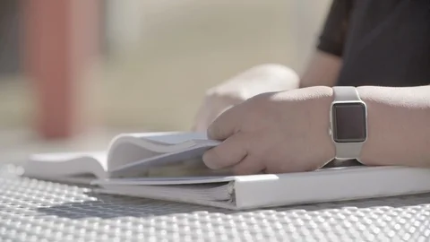Close Up of Hands With a Smart Watch Flipping Through Text Book Slow Motions Video stock 125707039