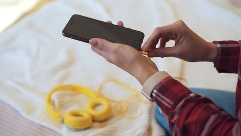 Close up hands with smartphone, man holding phone and connects headphones, home Stock Footage 87630940