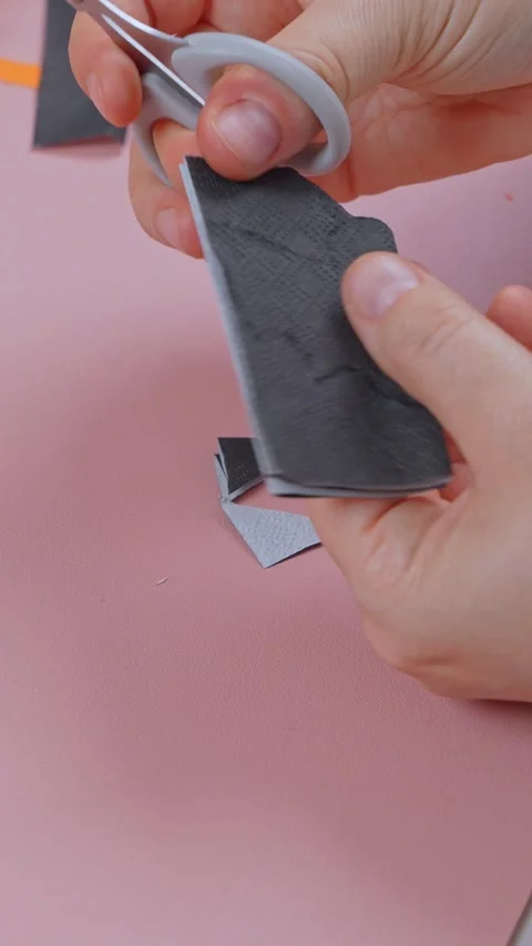 Close up hands snipping shapes into a folded black napkin with nail scissors Video stock 347105133