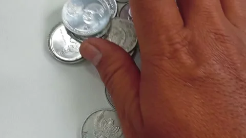 Close-up of hands sorting a coin collection.a white background Stock Footage 299736016