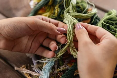 Close-up of hands sorting through a pile of embroidery floss. A large number  Stock Photos