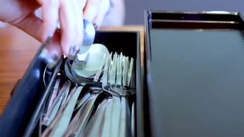 Close up of hands sorting through shiny metal cutlery in a black organizer bo Vídeos de archivo 333351230