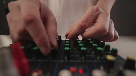 Close-up hands of sound engineer adjusting multiple knobs and levels on Stock Footage 323446702