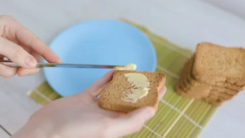 A close-up of hands spreading butter on a slice of toasted bread, Stock Footage 232959521