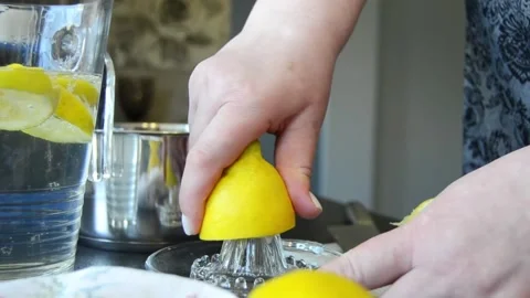 Close-up of hands squeezing fresh lemon using a manual juicer Stock Footage 344660965