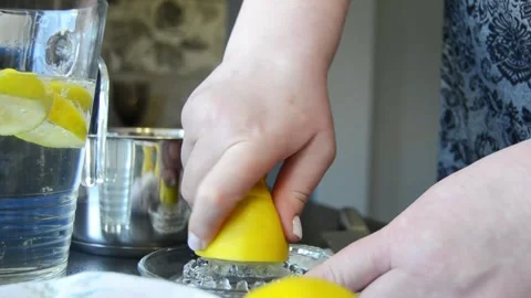 Close-up of hands squeezing fresh lemon using a manual juicer Stock Footage 344661055