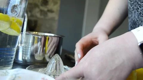 Close-up of hands squeezing fresh lemon using a manual juicer 스톡 동영상 344661205