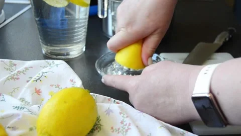 Close-up of hands squeezing fresh lemon using a manual juicer Stock Footage 344661420