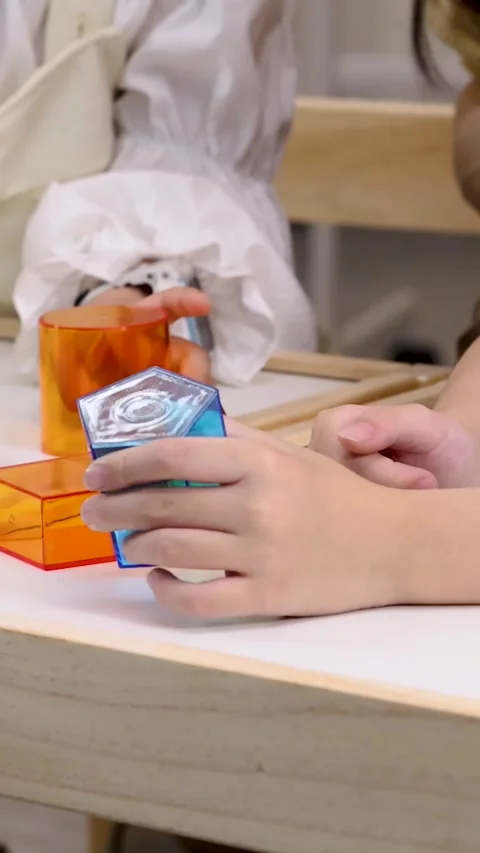 Close up of hands stacking colorful transparent geometric blocks on desk Stock Footage 327272465