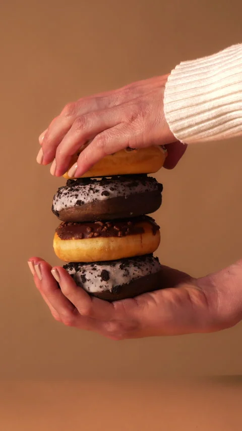 Close up of hands stacking the final vanilla glazed donut with colorful 動画素材 331233004