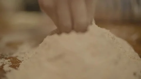Close-up of hands starting to make well in flour Stockbeeldmateriaal 336374658