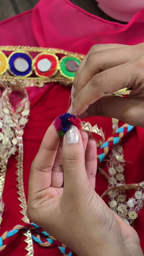 Close-up of hands stitching a colorful pompom embellishment onto a handcrafted c Stock Footage 337091468