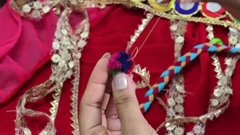 Close-up of hands stitching a colorful pompom embellishment onto a handcrafted c Stock Footage 337091477