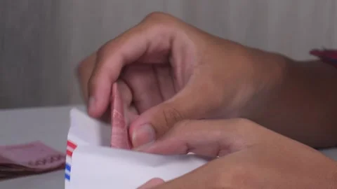 Close up of hands stuffing wage money into an envelope on table Stock Footage 277177735
