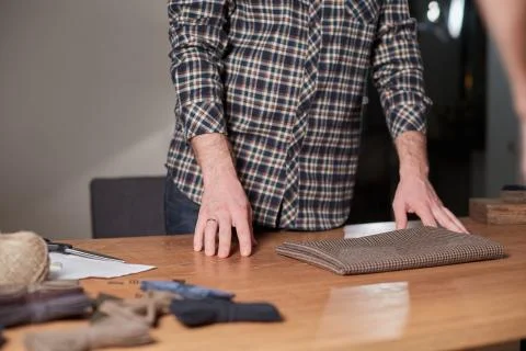 Close-up hands of Tailor, cutting wool fabric. Craftsman Makes rectangular Foto stock