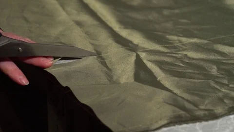 Close-up hands with tailor scissors cut through the khaki fabric. Stock Footage 124983061