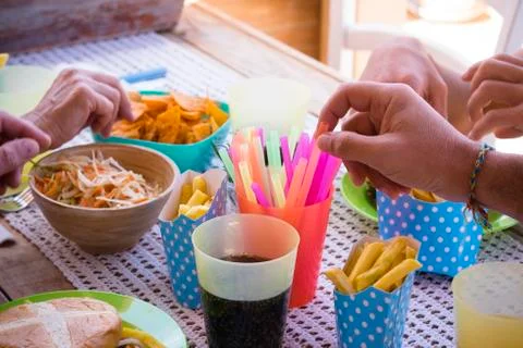 Close up of hands taking chips and food of the table in a happy party in a ho Foto stock